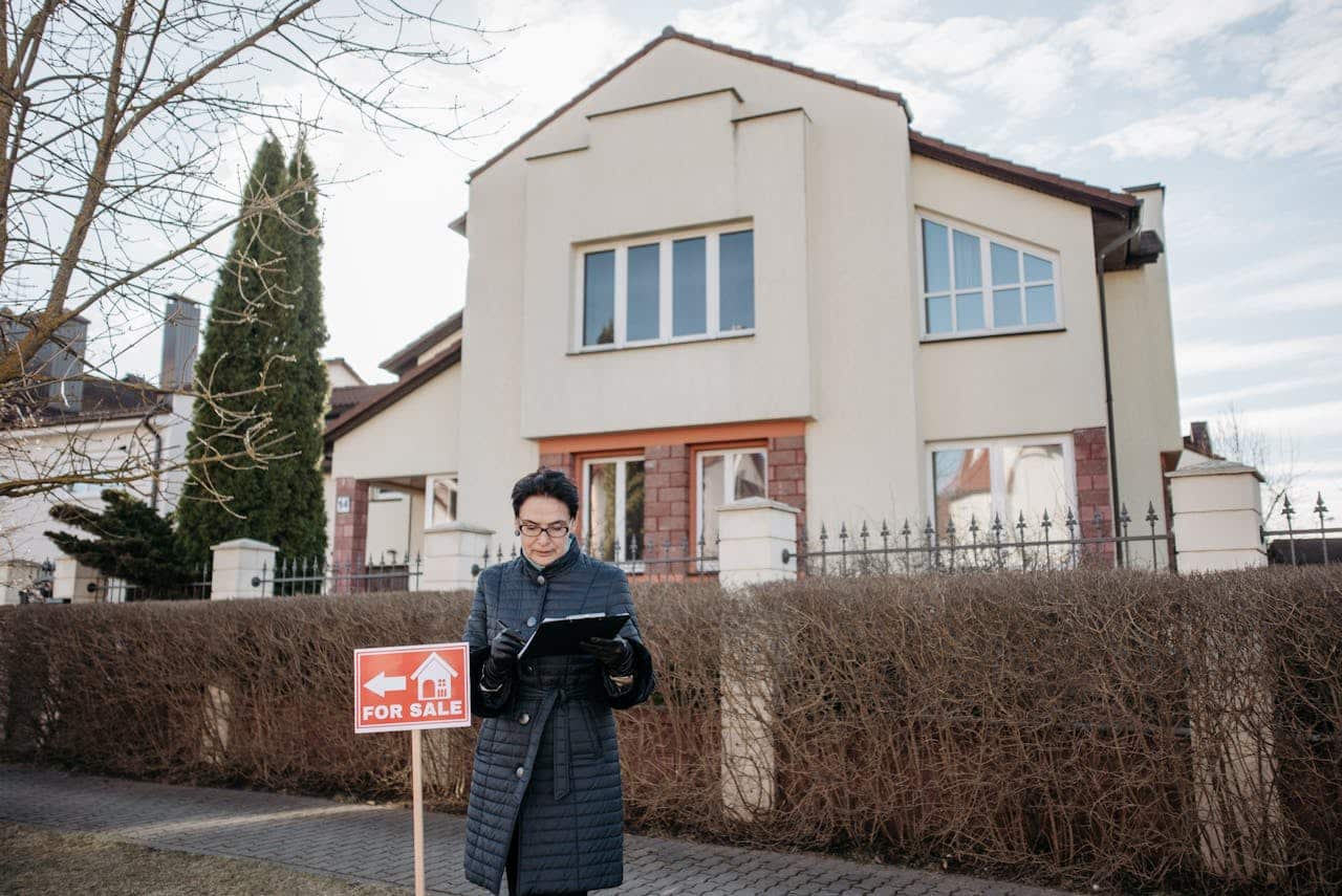 Real estate agent reviewing property details in front of a house for sale.