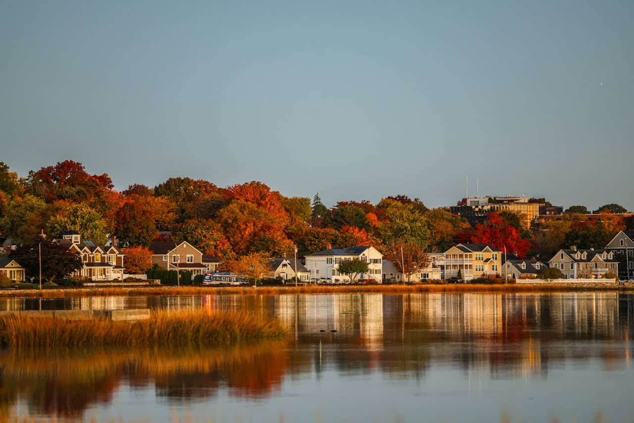 Scenic view of a lake surrounded by autumn foliage and charming houses.