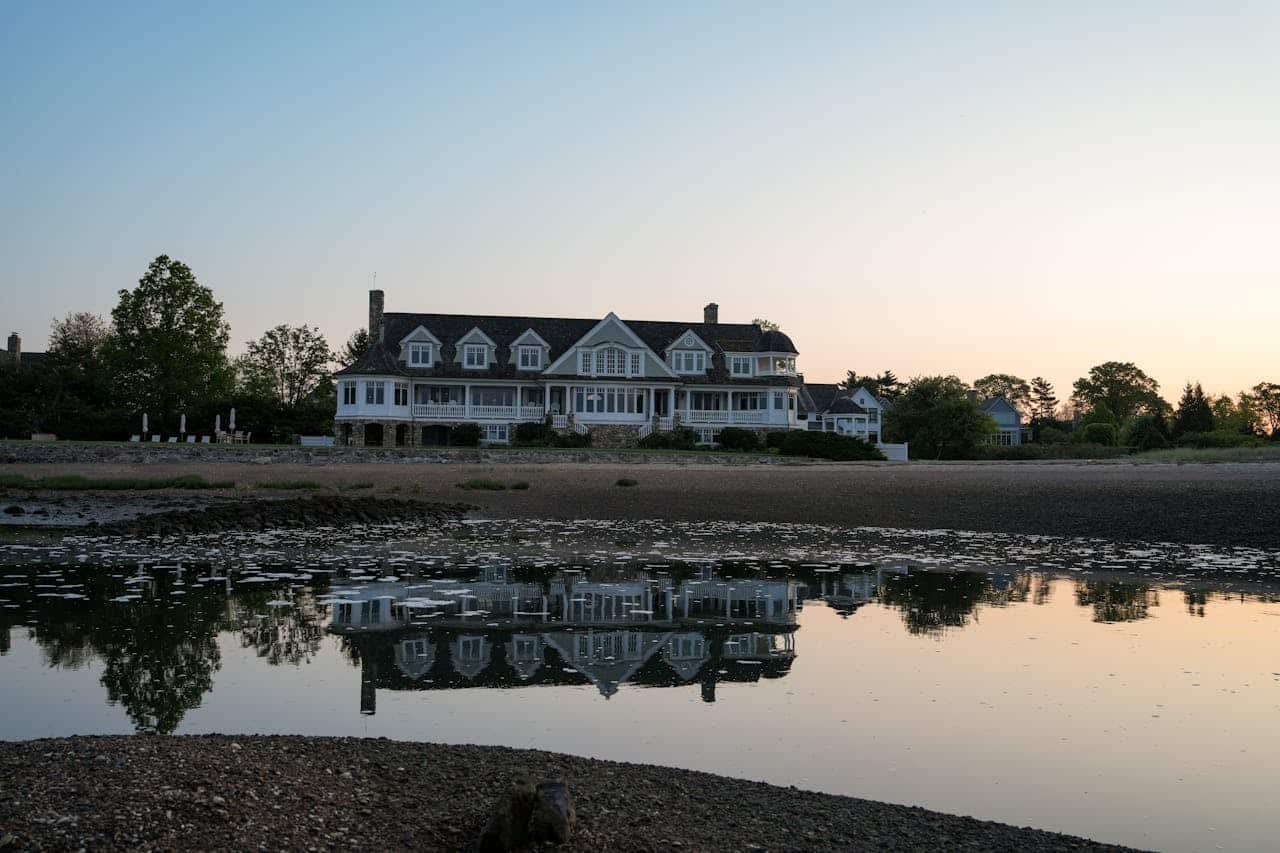 A beautiful coastal mansion reflecting in the water during sunset.