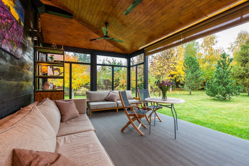 A cozy sunroom with comfortable seating and a view of autumn foliage.