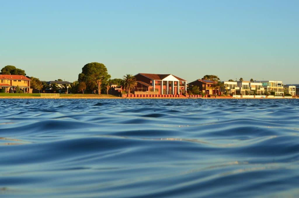Peaceful lake houses surrounded by greenery and sparkling water.