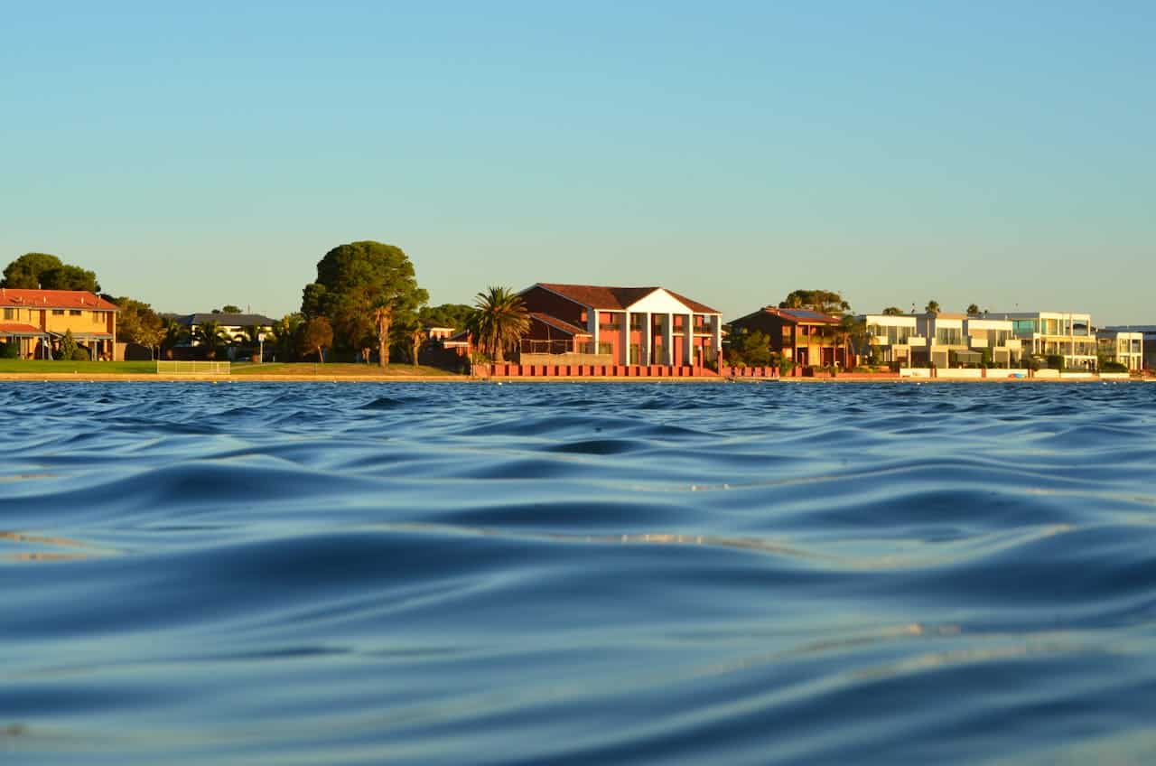 Peaceful lake houses surrounded by greenery and sparkling water.