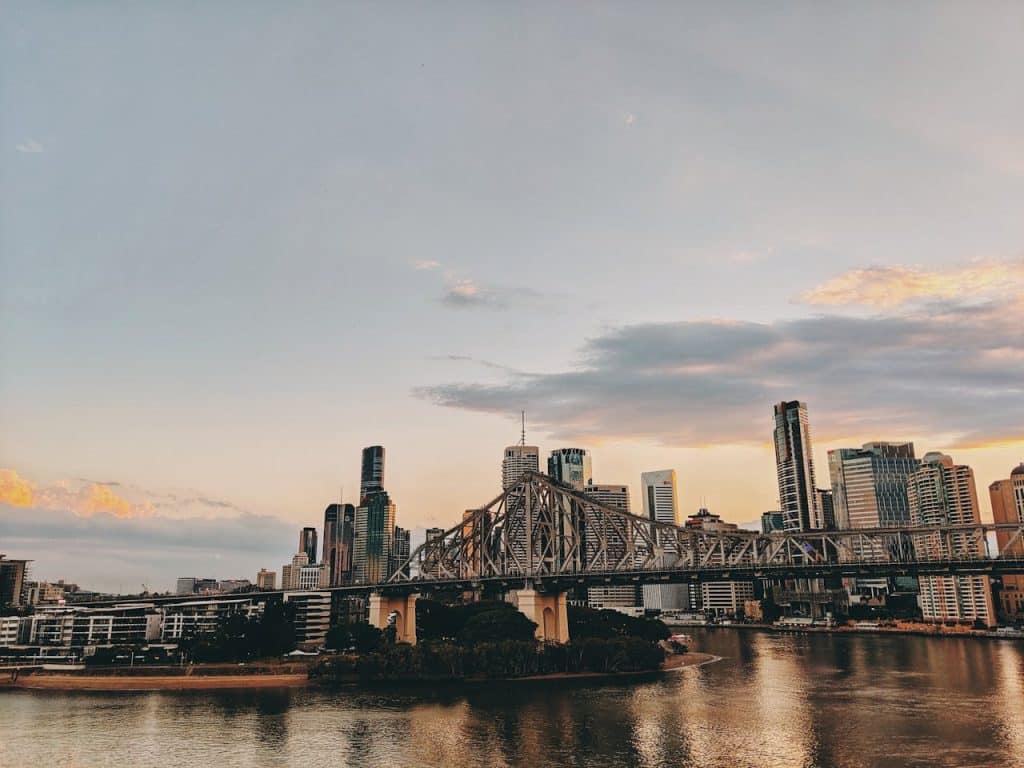 A stunning view of Brisbane city during sunset with the iconic bridge and skyline reflected in the river.
