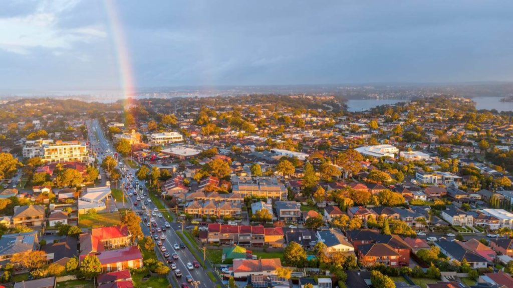 Aerial view of a suburban area with a rainbow in the sky.