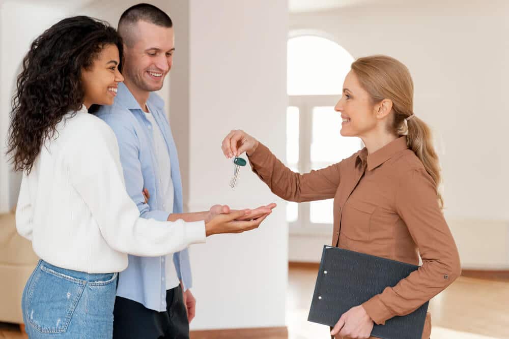 Happy couple receiving house keys from real estate agent in new home.