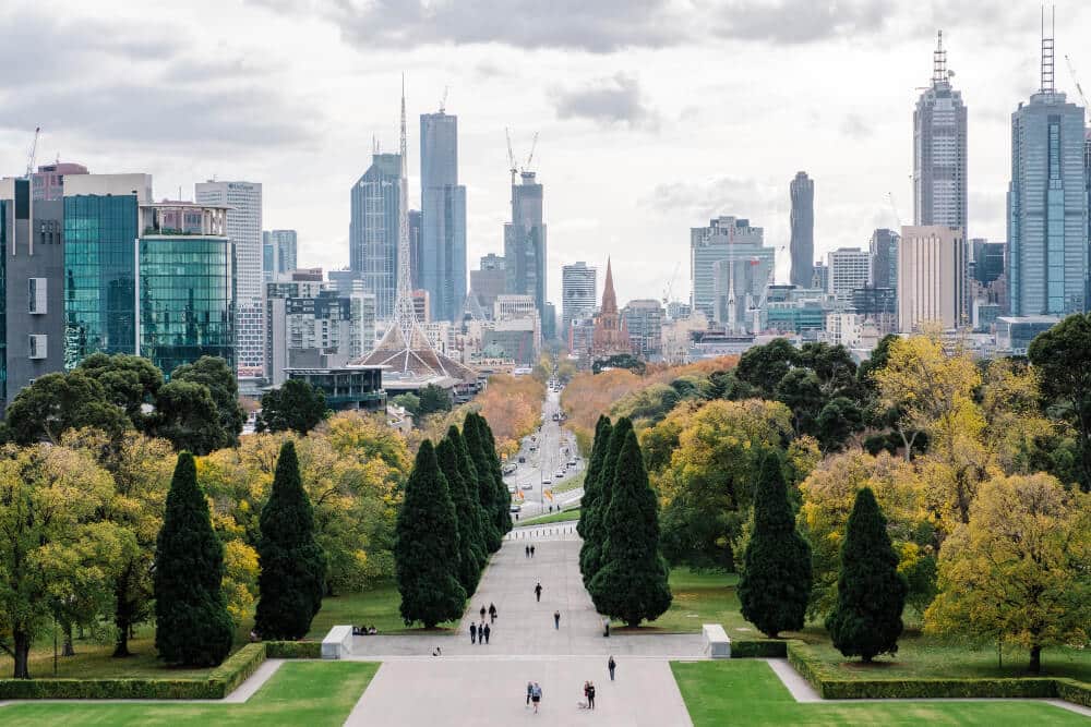 A panoramic view of Melbourne's city skyline with autumn foliage in the foreground.