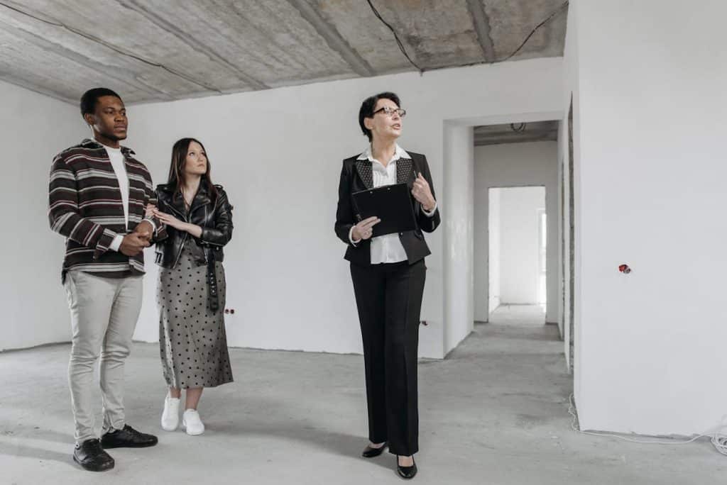 A real estate consultant discussing with clients in an empty room.