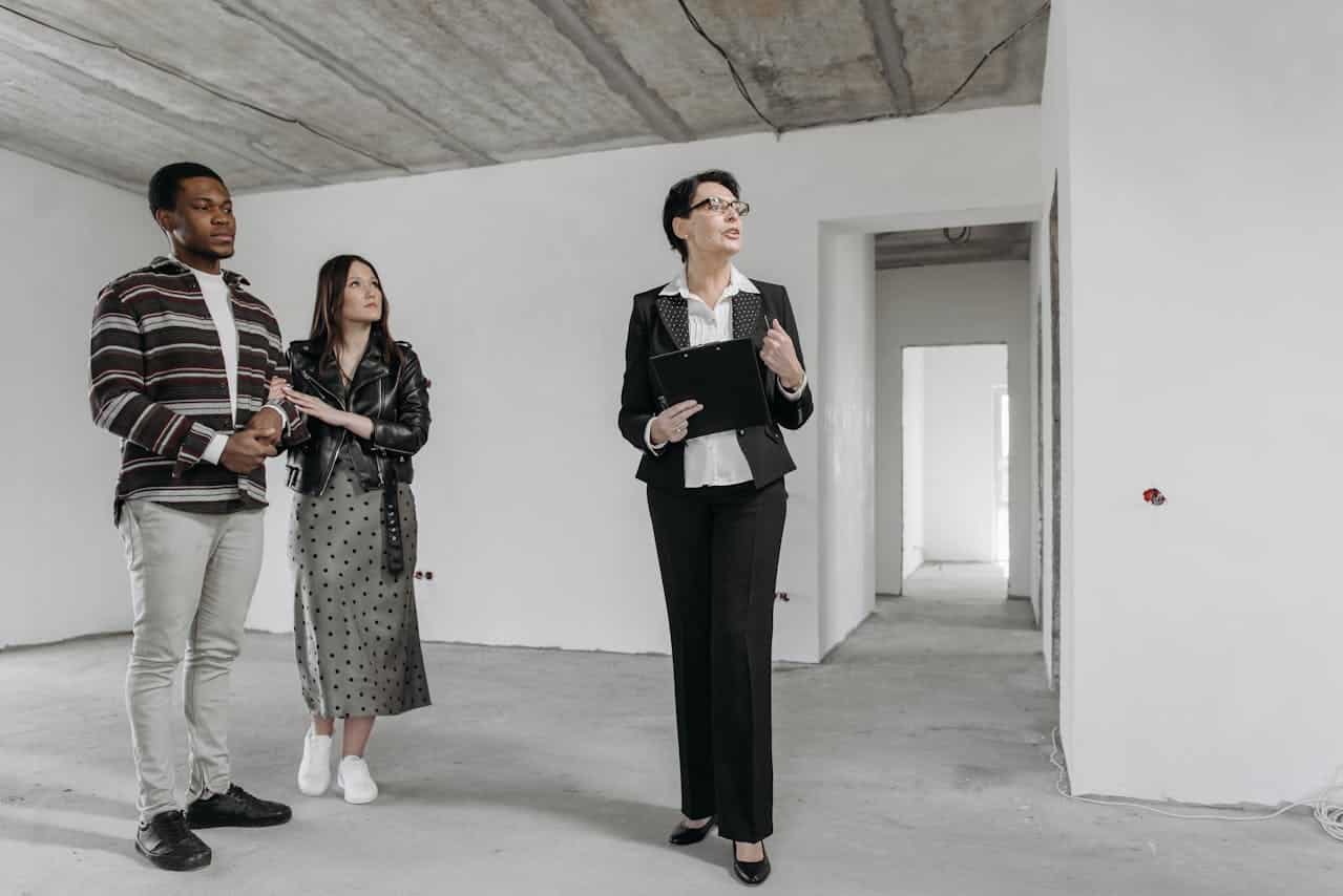 A real estate consultant discussing with clients in an empty room.