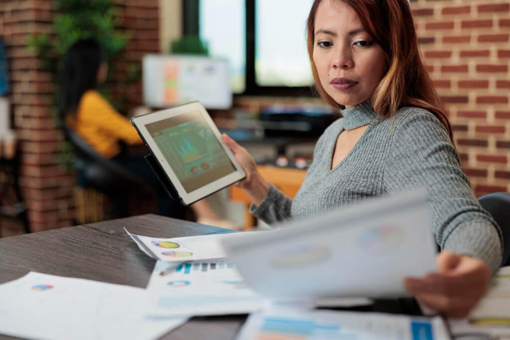 Business woman analyzing data on a tablet in a modern office.