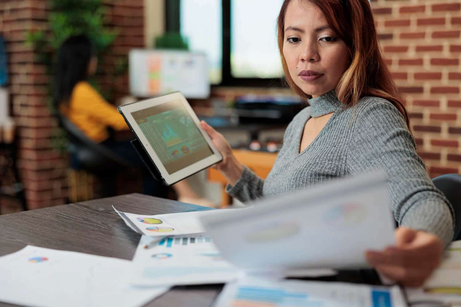 Business woman analyzing data on a tablet in a modern office.