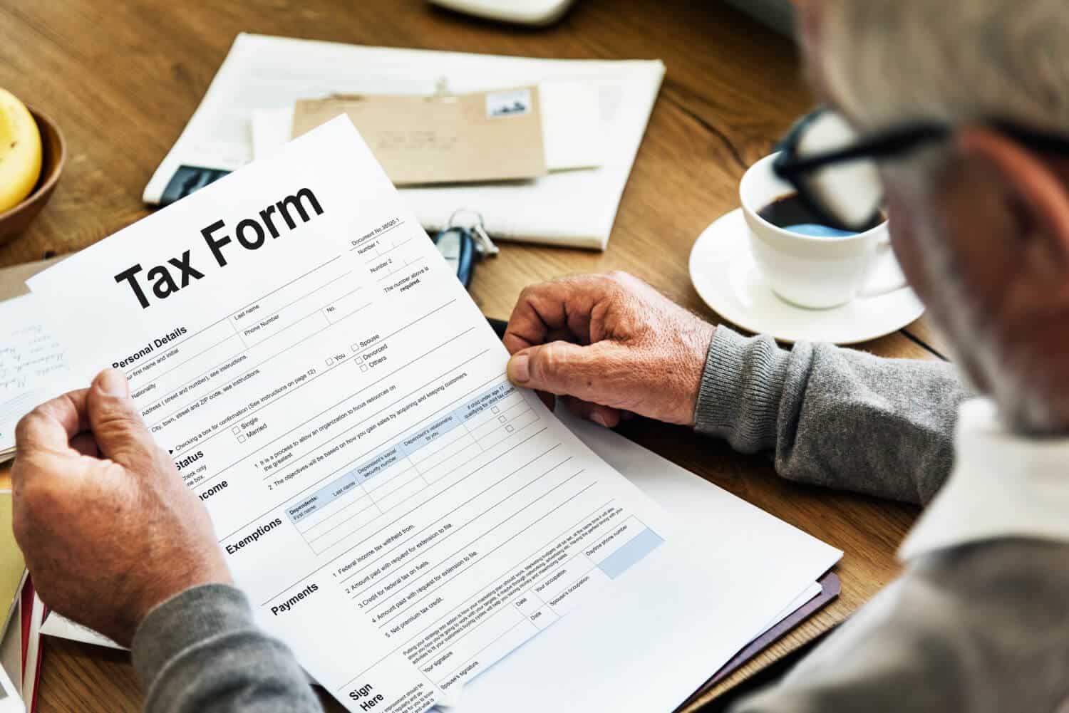 A person reviewing a tax form at a wooden table.