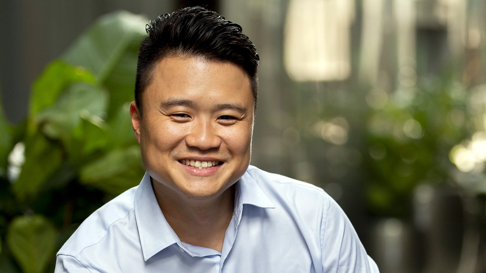 Simon Loo, founder of House Finder, smiling in a light blue shirt with greenery behind him